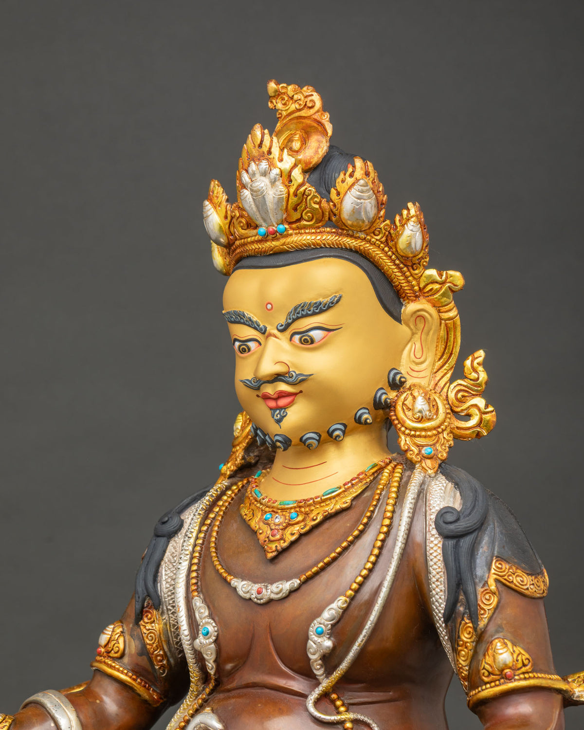 Dzambhala Statue side close up of citron fruit, jewel-spitting mongoose and silver-plated robe folds