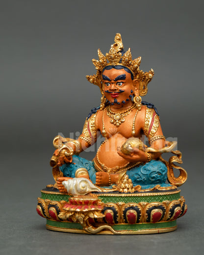 Dzambhala wealth deity statue seated on lotus throne holding citron fruit and mongoose symbols.