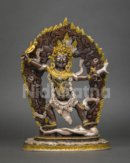 Ekajati statue standing on a prone figure, with gold and silver accents and a flame halo
