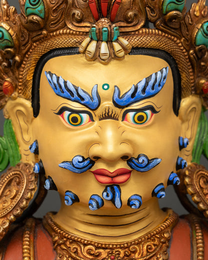 face close up of dzambhala buddhist deity with gold painted expression and piercing eyes