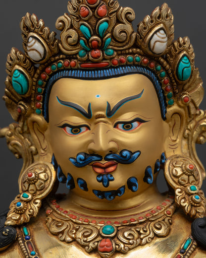 face close up of dzambhala statue, wrathful expression with gold gilded finish