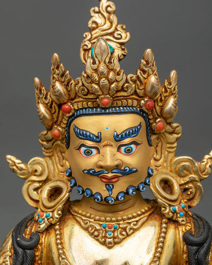 Face close-up of Dzambhala wealth god statue with serene expression and crown details