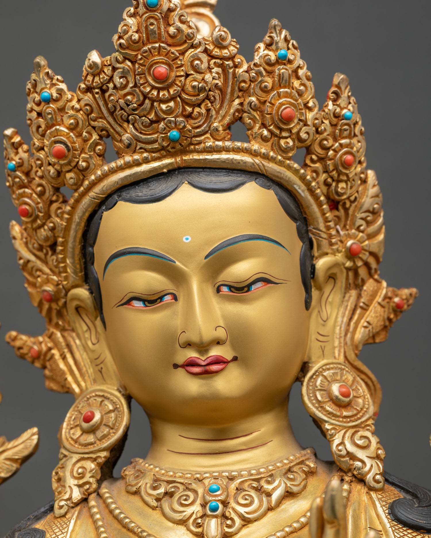 Face close-up of Green Tara Bodhisattva, gold fire-gilded, serene compassionate expression