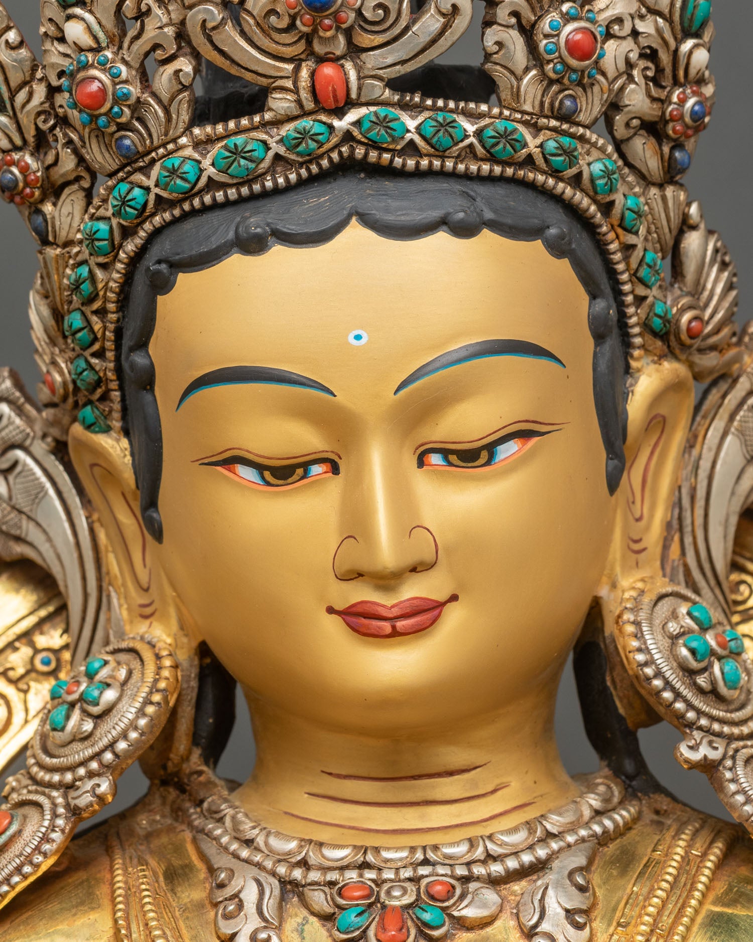 Face close up of Green Tara statue with hand-painted gold features and serene expression