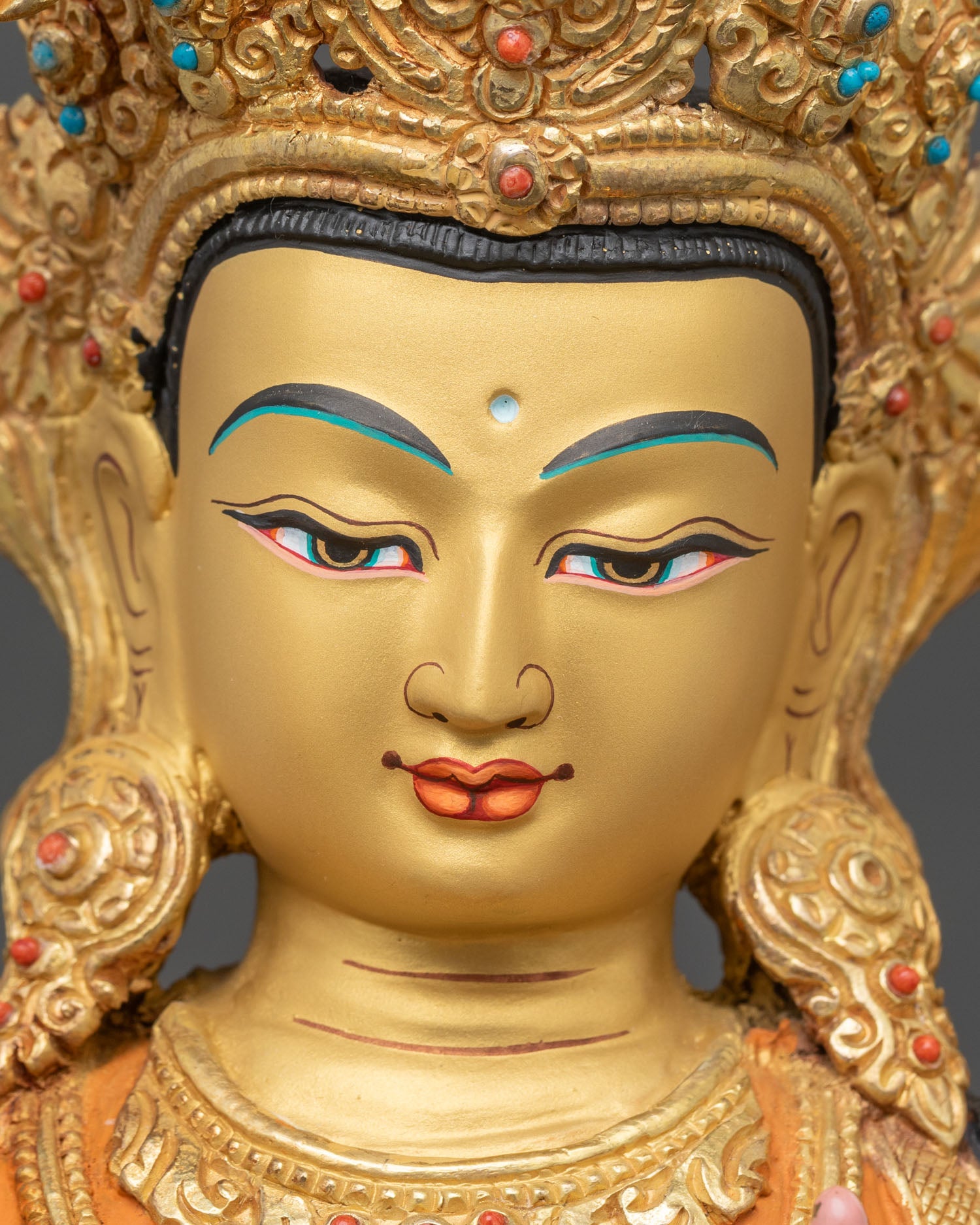 Face close up of Manjushri Statue with gold painted expression and serene detail