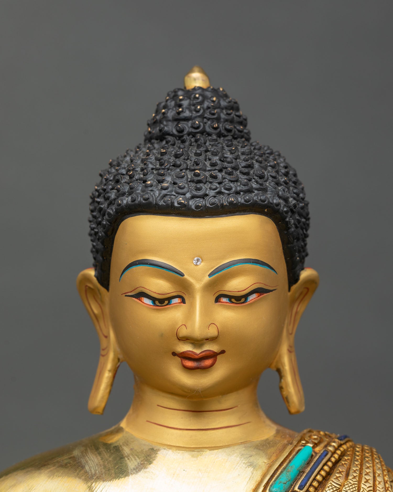Face close-up of Medicine Buddha Bhaisajyaguru with serene expression and gold finish