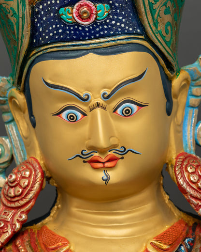Face close up of Padmasambhava Guru Rinpoche statue with serene eyes, gold gilded facial detailing Nepal