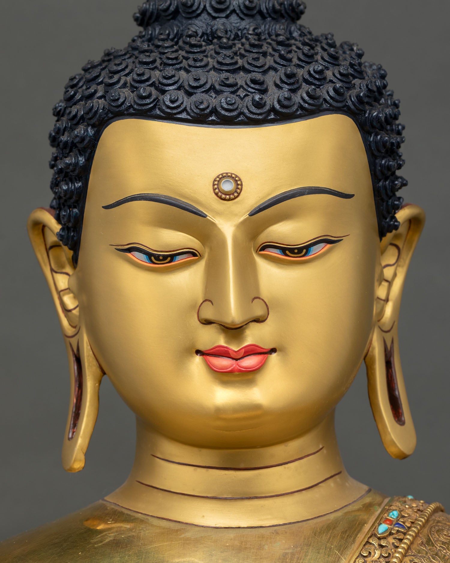 face close up of shakyamuni buddha statue with serene expression and gold painted face