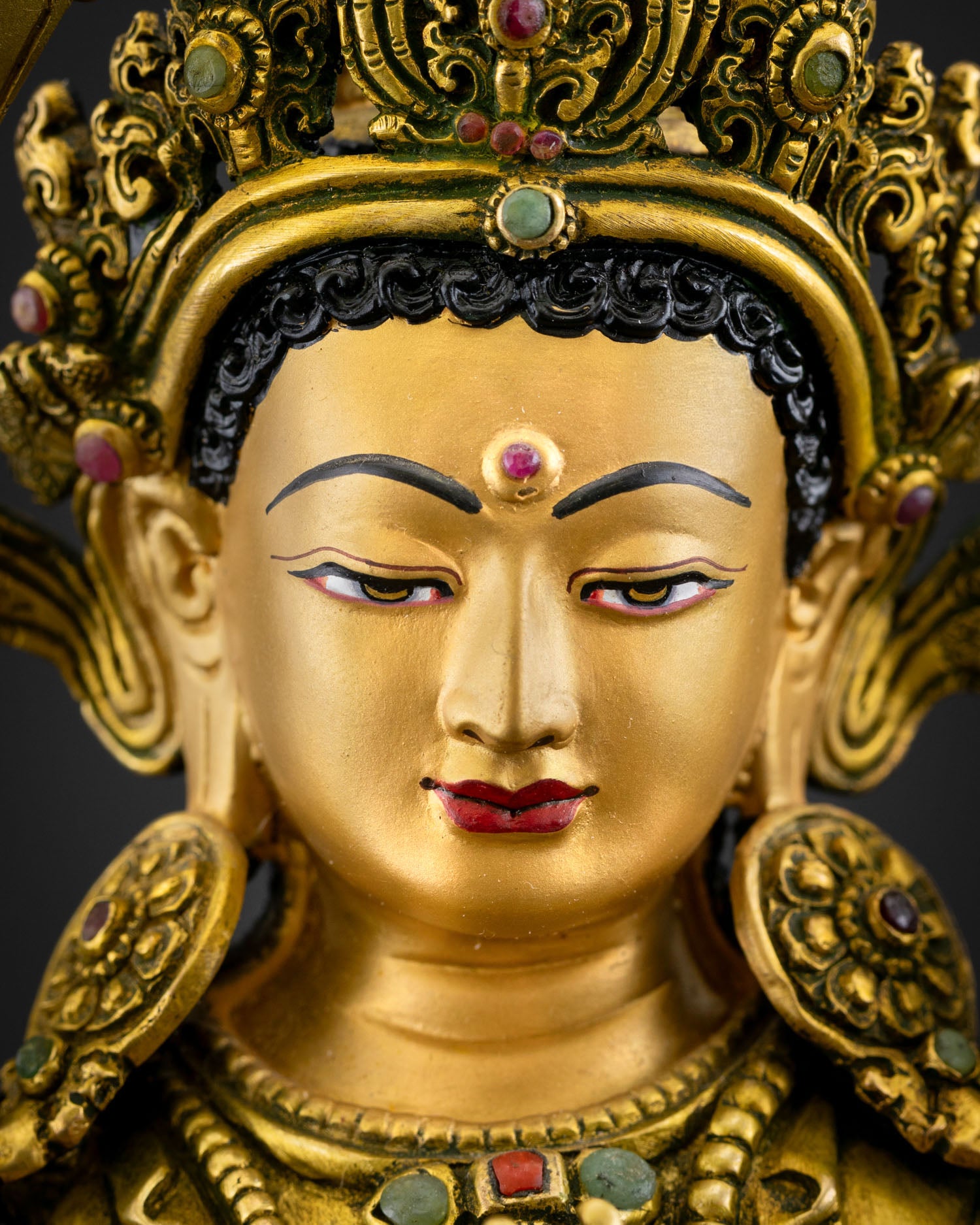 Face close-up of Simhanada Manjushri with serene gold-painted expression
