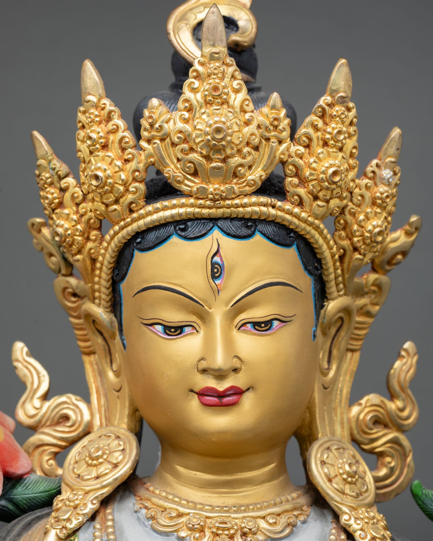 face close-up of white tara statue with peaceful gold-painted expression