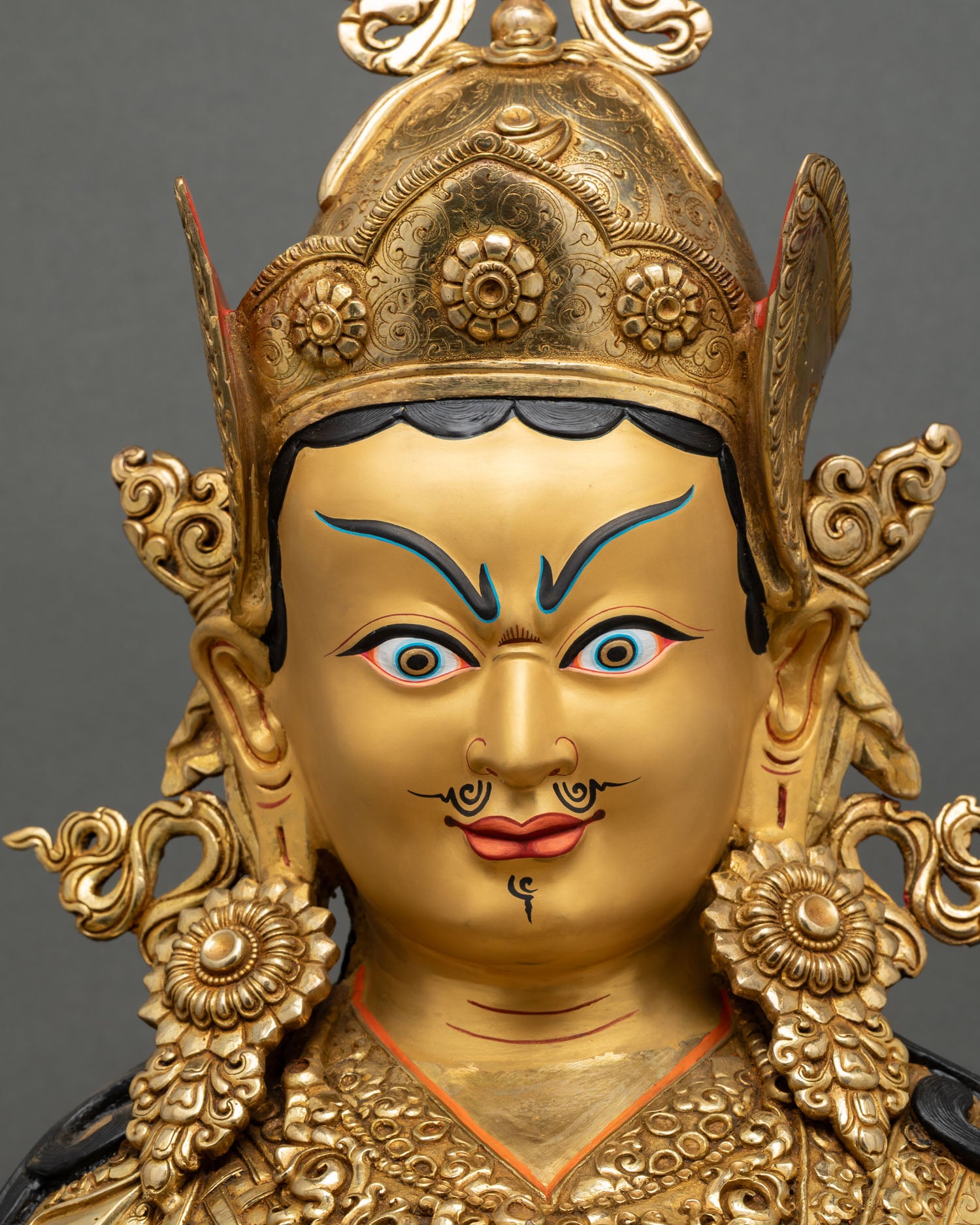 face close up padmasambhava statue, serene expression with lotus hat, intricate 3d carved details and gold gilded finish