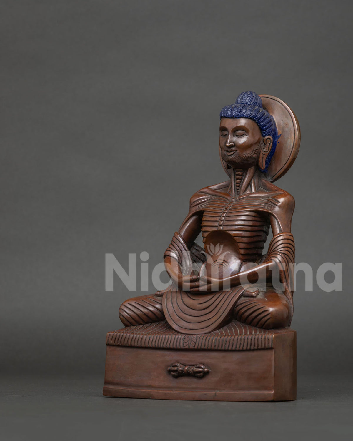 Fasting buddha seated in dhyana mudra with round halo and ornate pedestal.