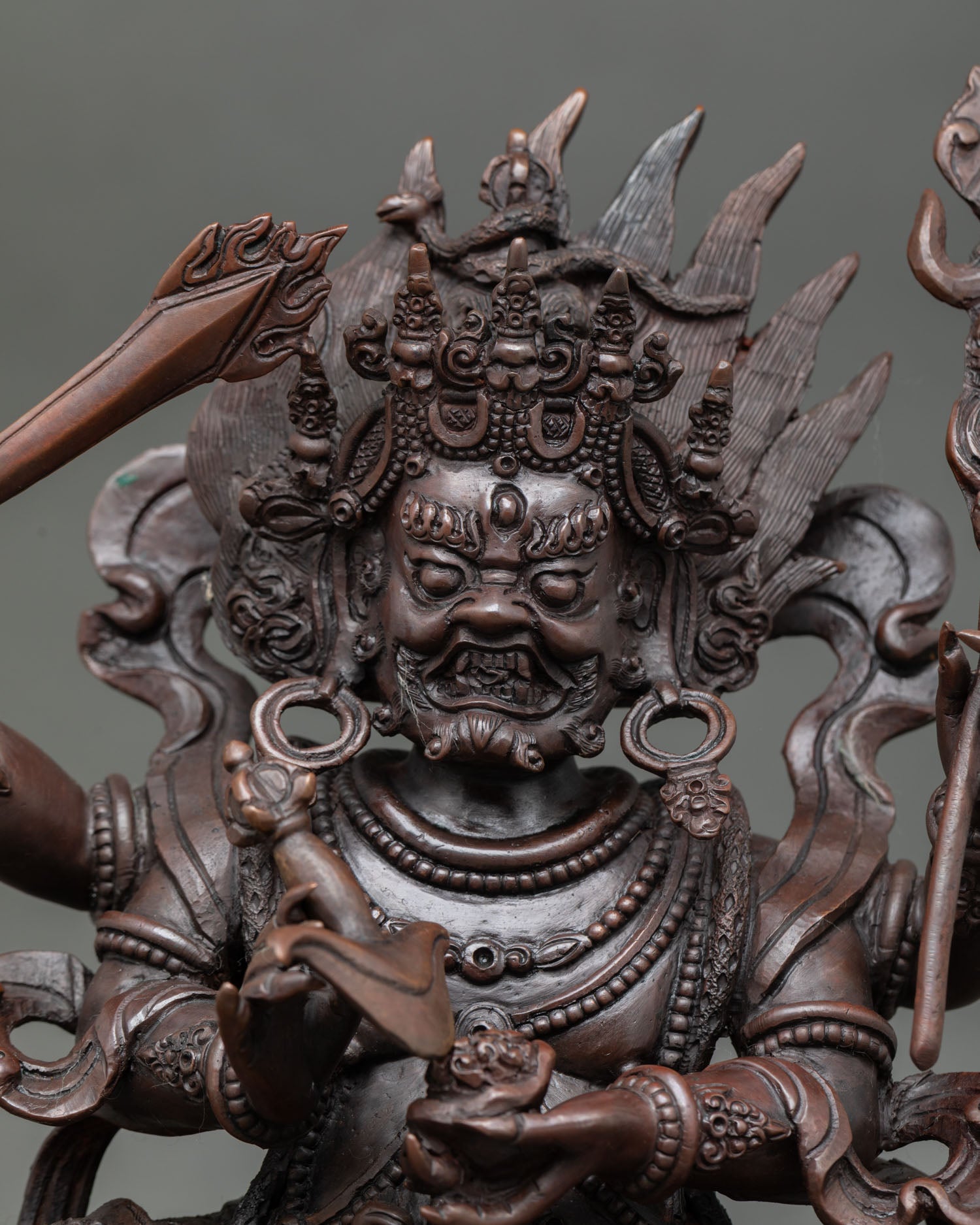 Four Armed Mahakala close up fierce expression detail copper statue with oxidized finish showing intricate facial features wrathful Mahakala Buddhist deity sculpture.