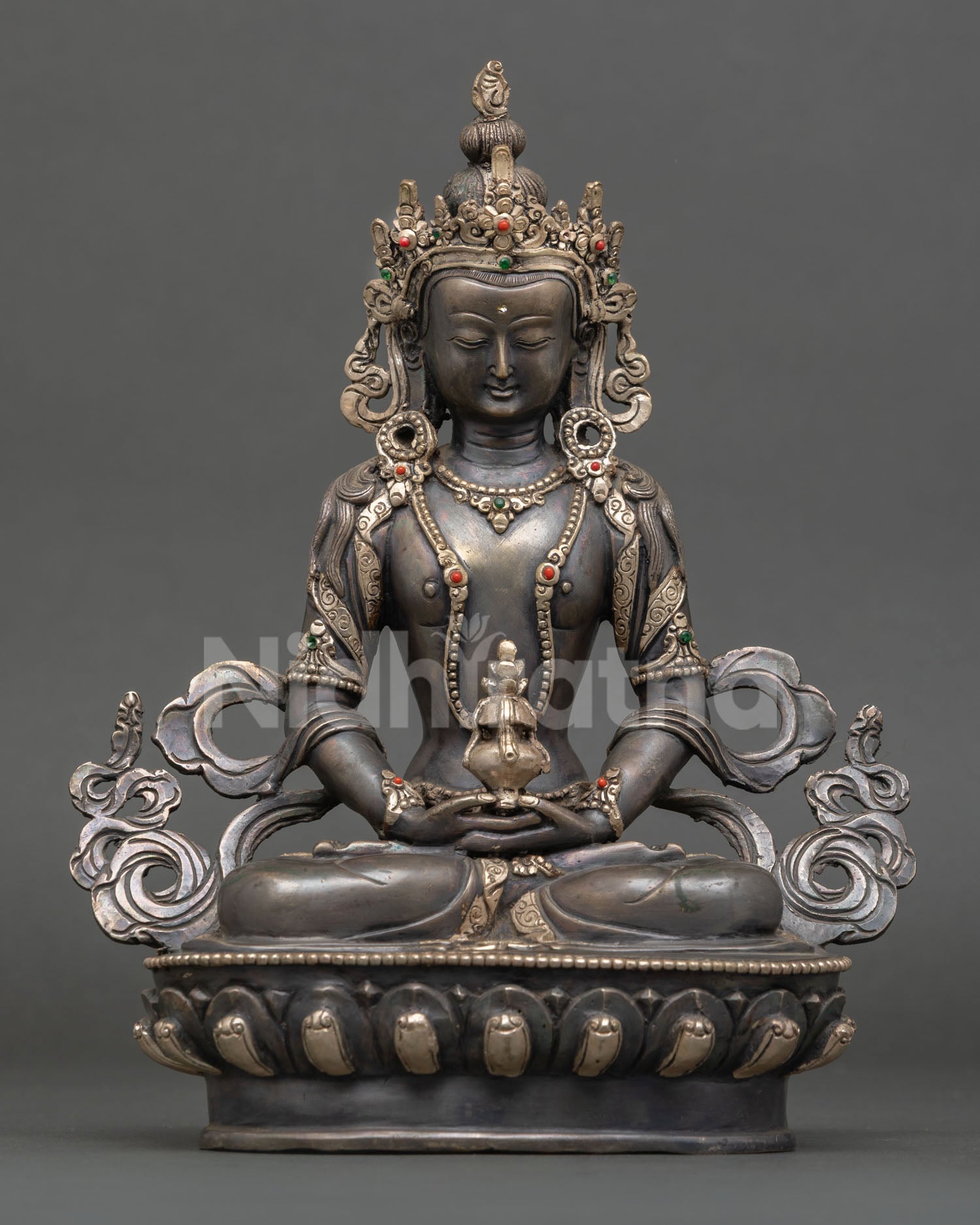 Front view of Amitayus statue handcrafted in copper with oxidized and silver plated finish seated on ornate lotus pedestal holding long life