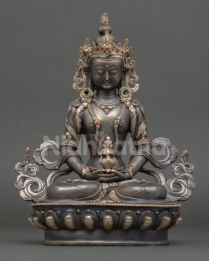 Front view of Amitayus statue handcrafted in copper with oxidized and silver plated finish seated on ornate lotus pedestal holding long life