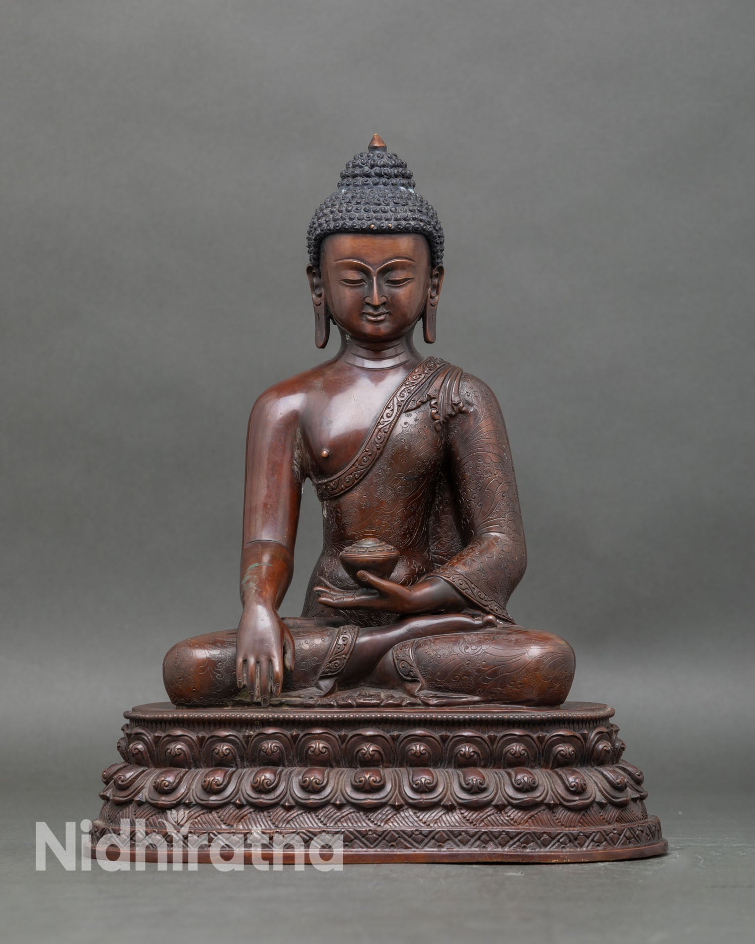 Front view of Buddha Shakyamuni statue with oxidized copper and lotus pedestal