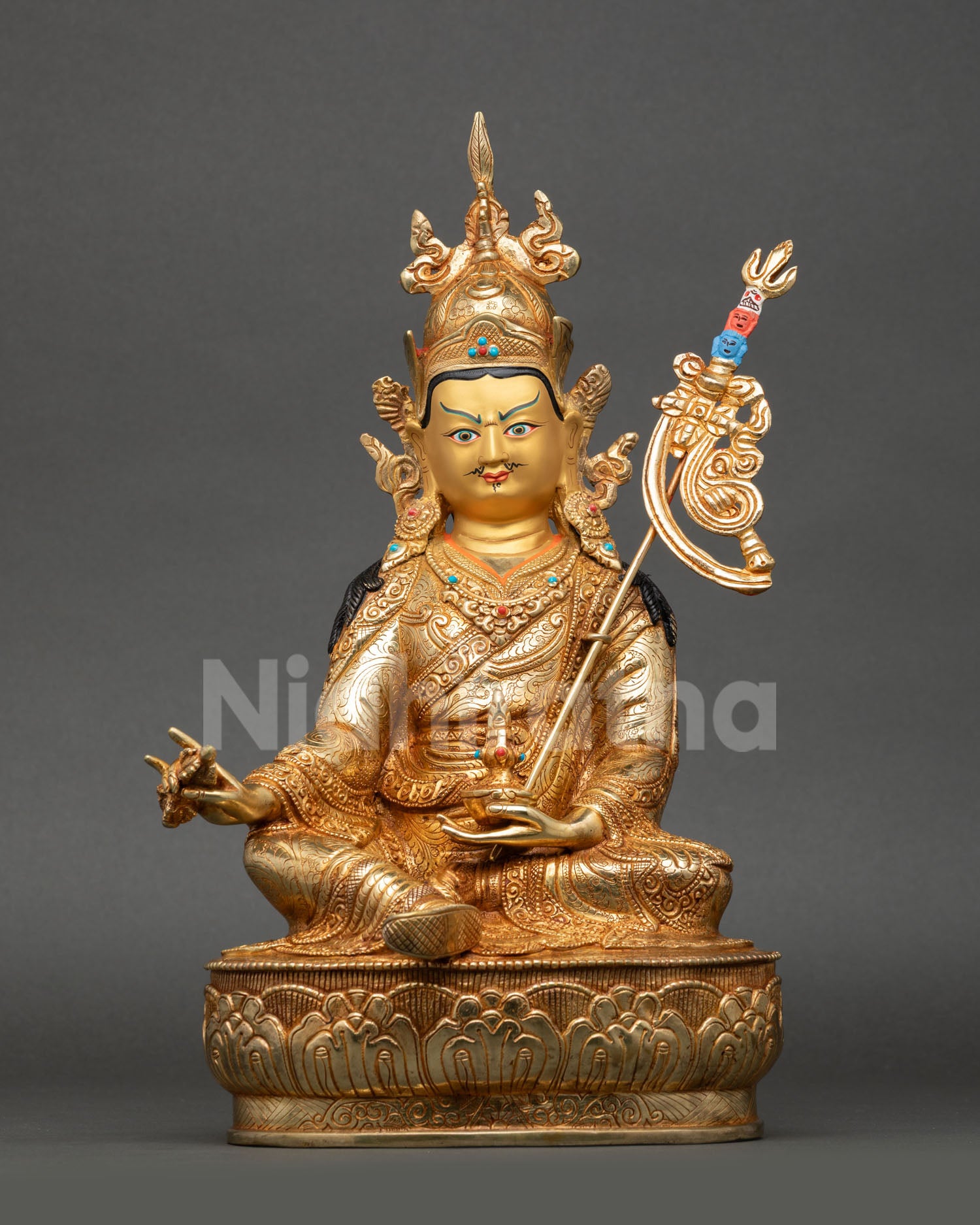 Front view of Guru Rinpoche statue seated on lotus pedestal holding vajra skull cup khatvanga trident Nepal copper 24K gold sculpture 