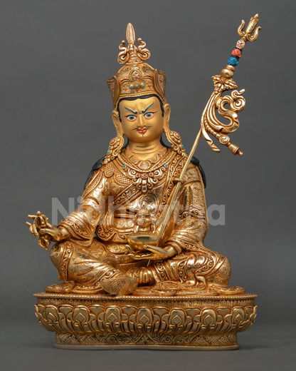 Front view of handmade Guru Rinpoche statue in copper with 24K gold gilding seated on lotus pedestal holding vajra and skull cup