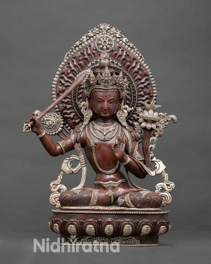 Front view of Manjushri statue handcrafted by Newari artisan in Nepal oxidized copper, seated on lotus throne with silver plated detailing and radiant halo