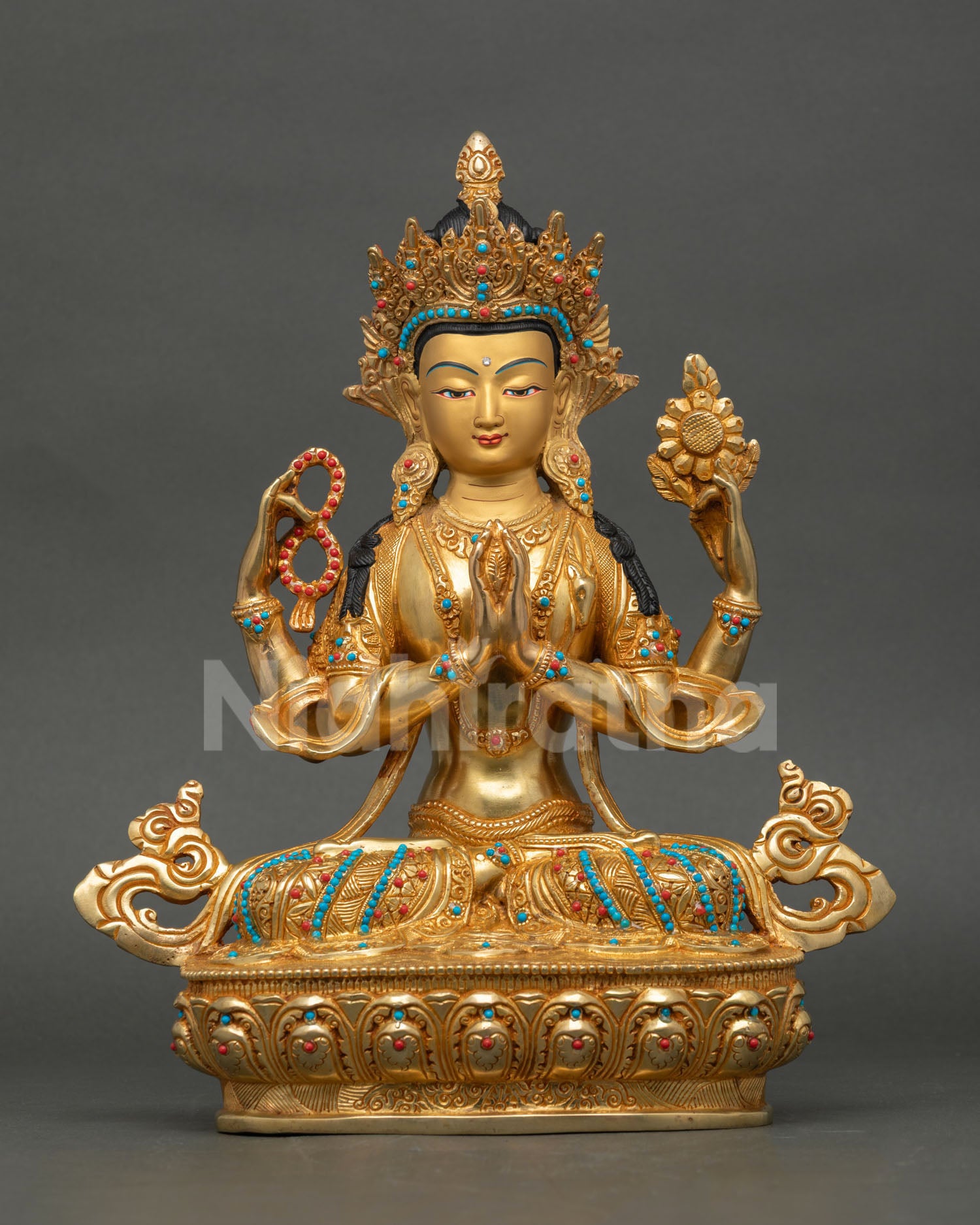 Front view of Chenrezig statue handmade in copper with gold painted face, turquoise and coral stones, seated on lotus seat from Nepal