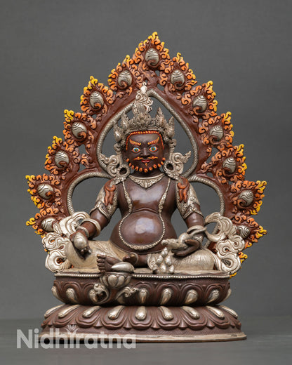 Front view of Dzambhala statue seated on lotus with silver-plated oxidized copper finish and halo