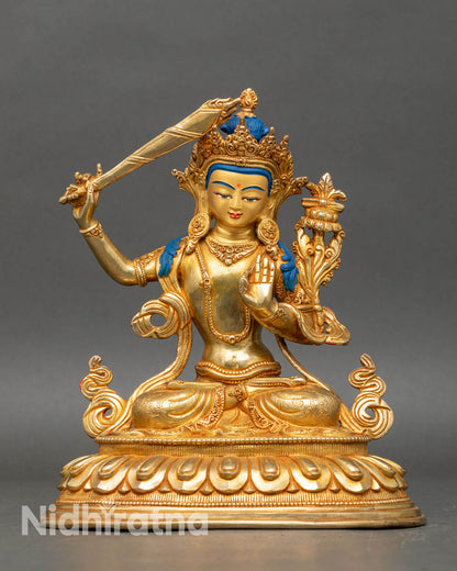 Front view of four-armed Manjushri statue seated on a lotus, made of copper with gold gilding from Nepal.