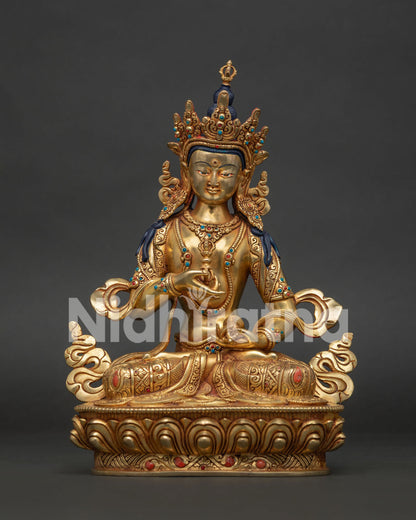 Front view of gold fire-gilded Vajrasattva statue from Nepal seated on a lotus, holding vajra and bell.