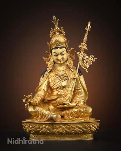 Front view of gold-gilded Guru Rinpoche statue seated on a lotus pedestal