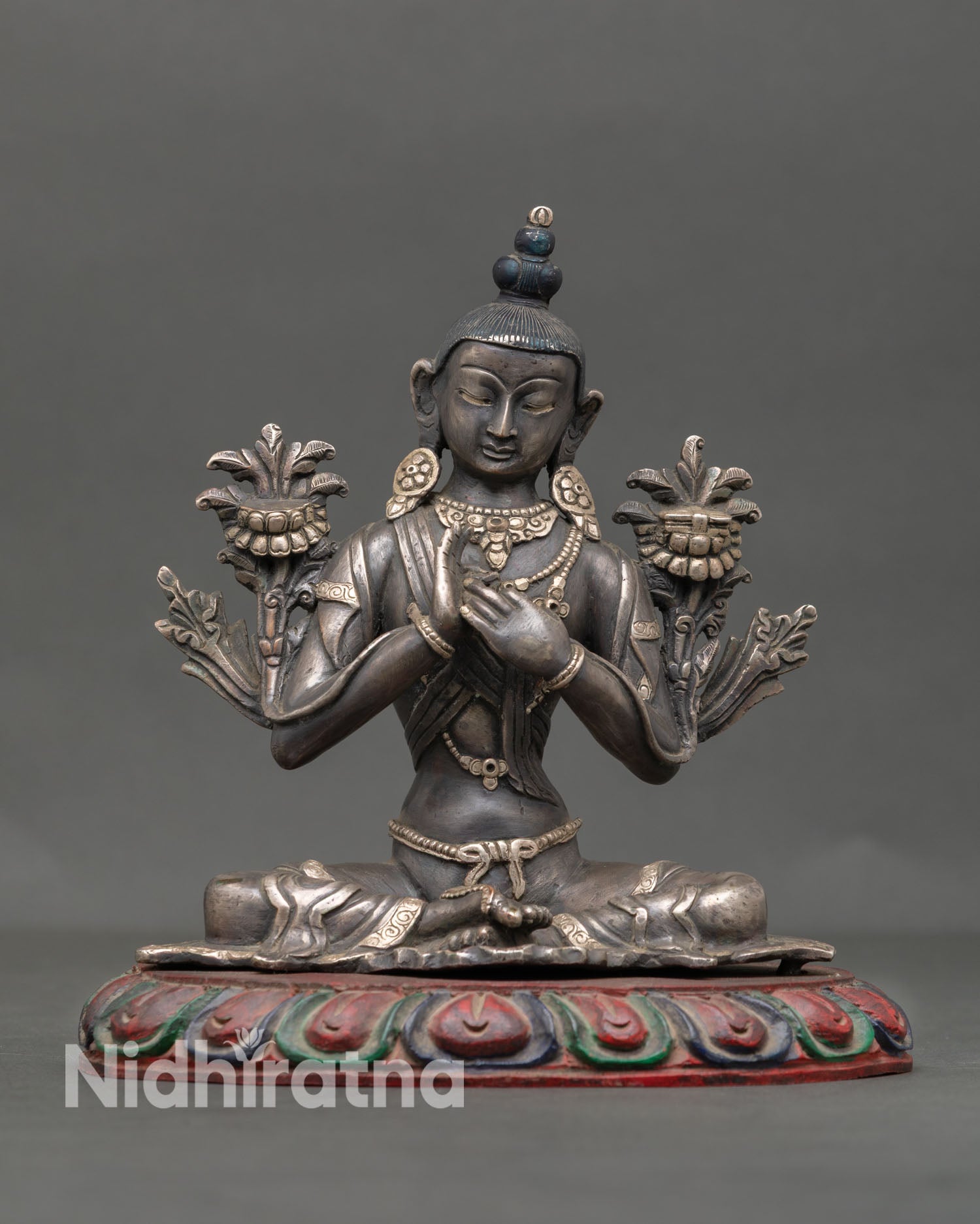 Front view of handcrafted Avalokiteshvara Chenrezig statue from Nepal in oxidized copper with silver plated jewelry seated on lotus pedestal symbolizing compassion
