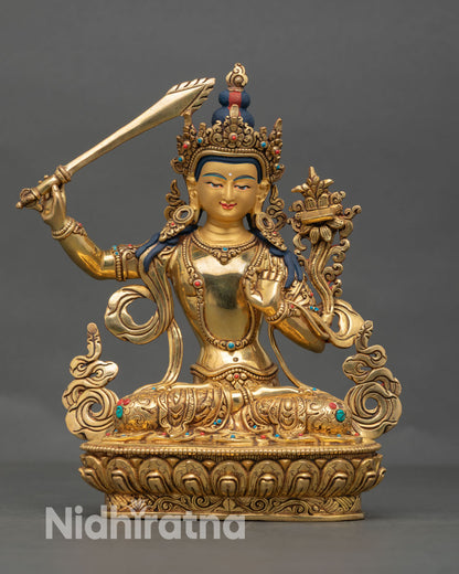 Front view of handcrafted Manjushree statue in gold gilded copper with serene face and lotus throne from Nepal
