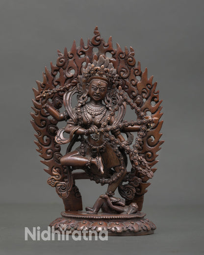 Front view of Kurukulla statue handcrafted in Nepal with oxidized copper finish and flaming halo on lotus base