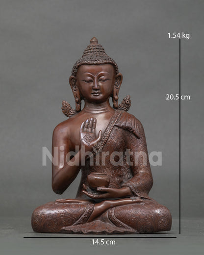 Front view of oxidized copper Amoghasiddhi Buddha statue in abhaya mudra with sacred bowl
