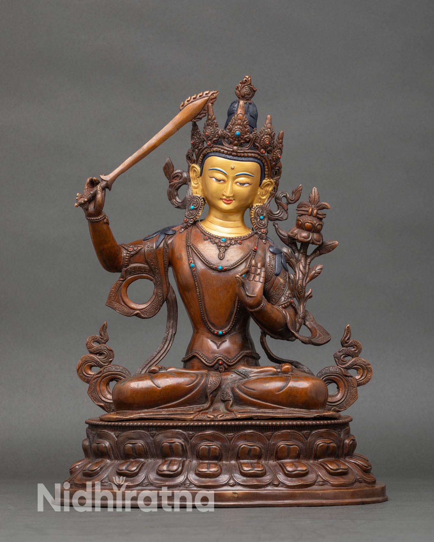 Front view of oxidized Manjushri statue from Nepal with gold-painted face and copper finish.