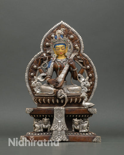 Front view of Saraswati statue handcrafted in Nepal with copper body, silver plated detailing, gold painted face, and ornate throne supported by snow lions