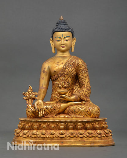 Front view of Tibetan Medicine Buddha statue handcrafted in Nepal with 24K gold fire gilded copper body serene gold painted face and lotus meditation posture