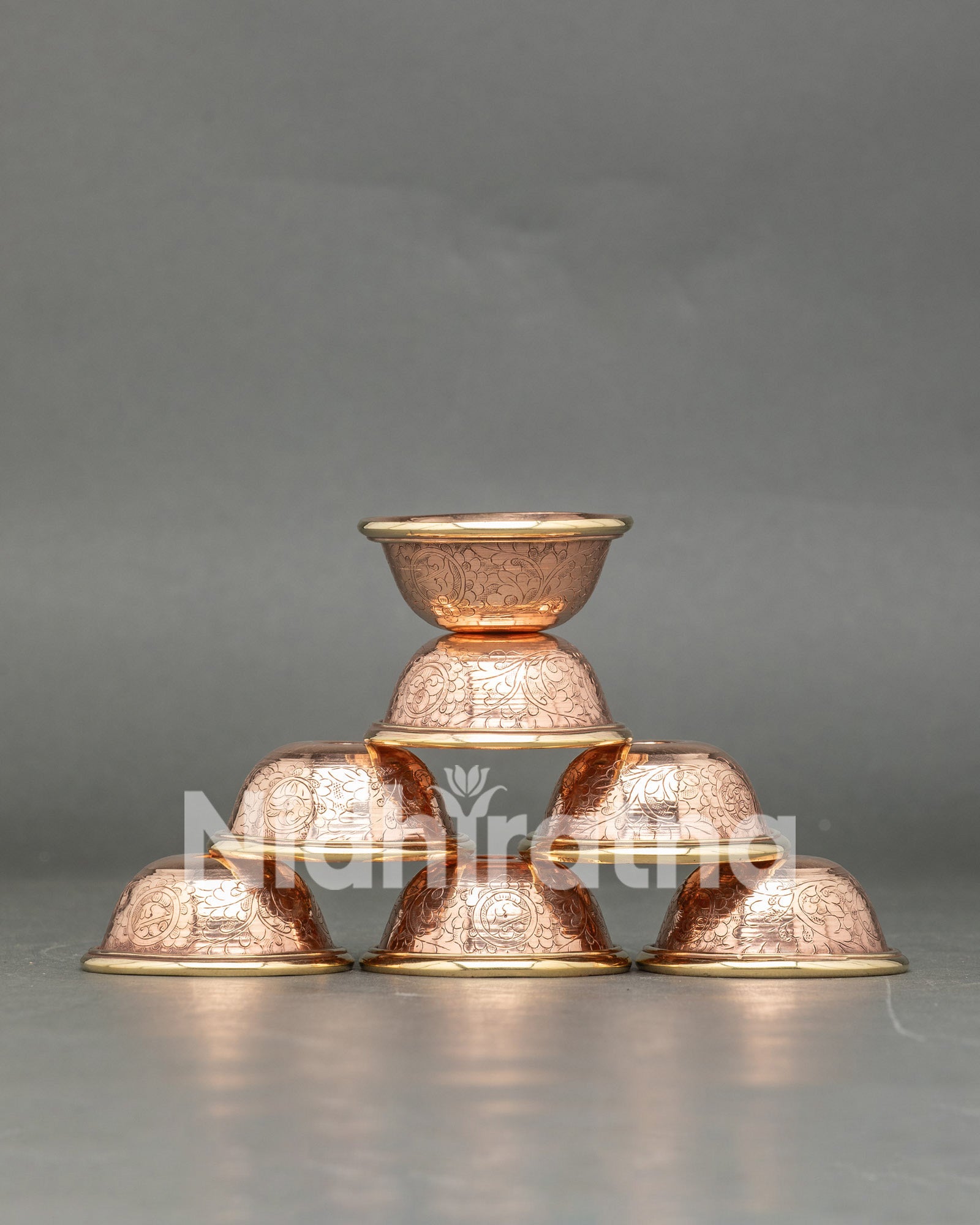 Front view seven copper water offering bowls handcrafted by Newari artisans from Patan Nepal