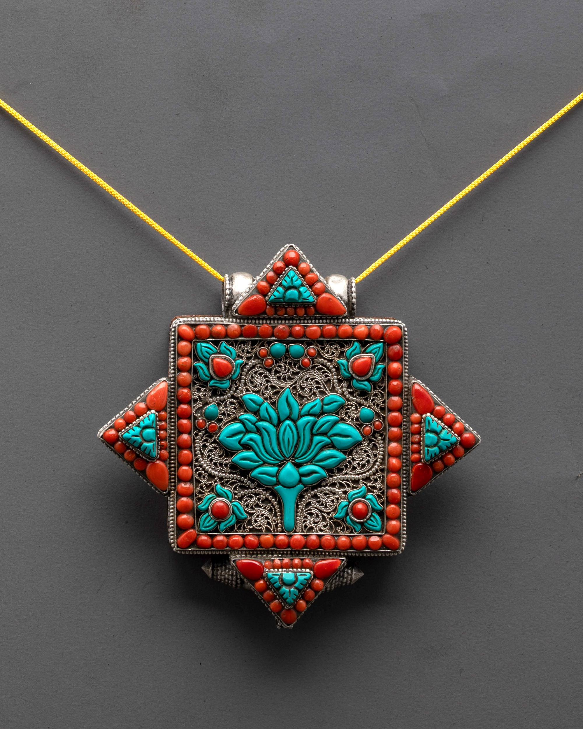 front view Tibetan lotus locket with coral and turquoise stones in silver filigree design
