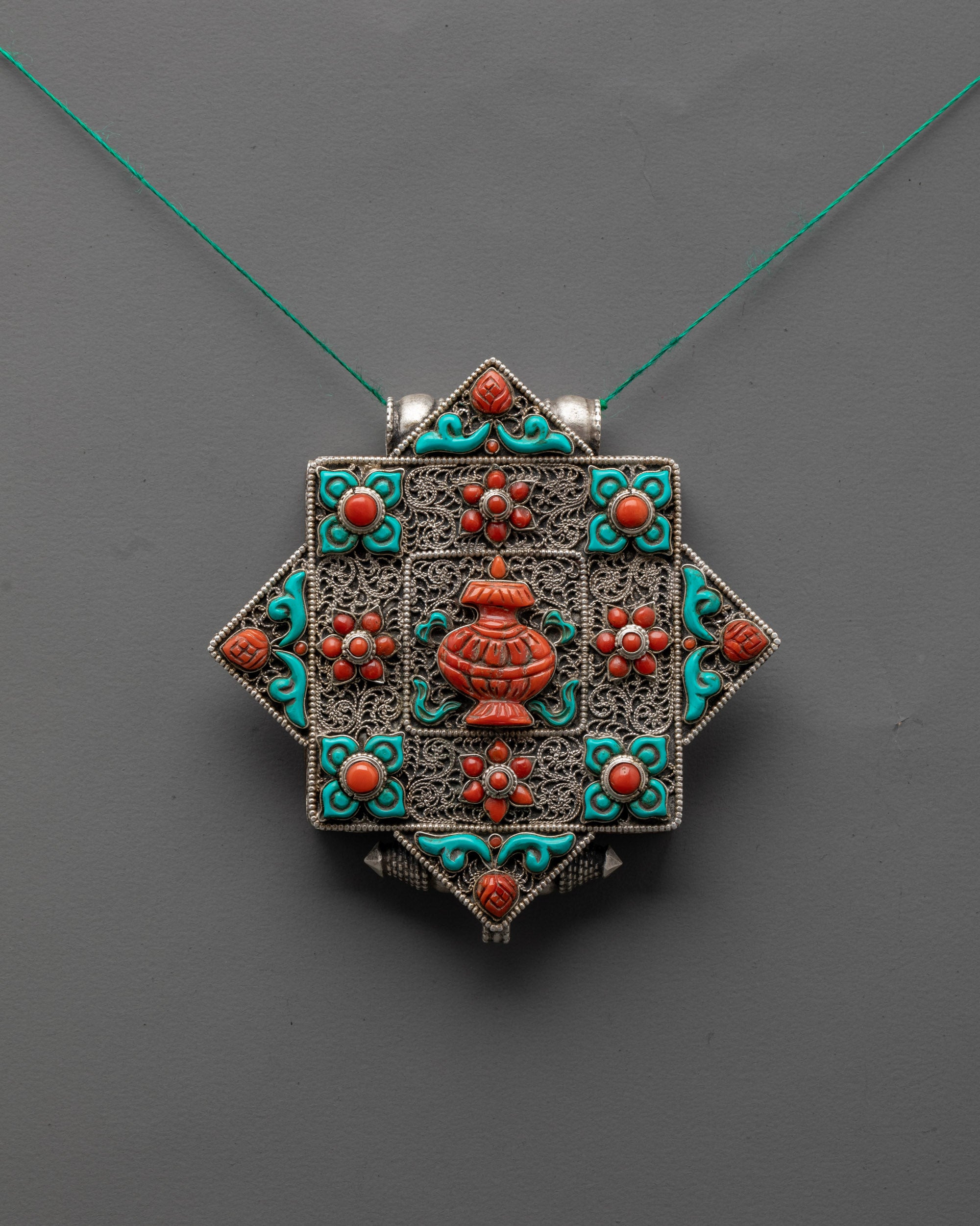 front view of artisan-crafted Treasure Vase locket with silver body and coral turquoise stones