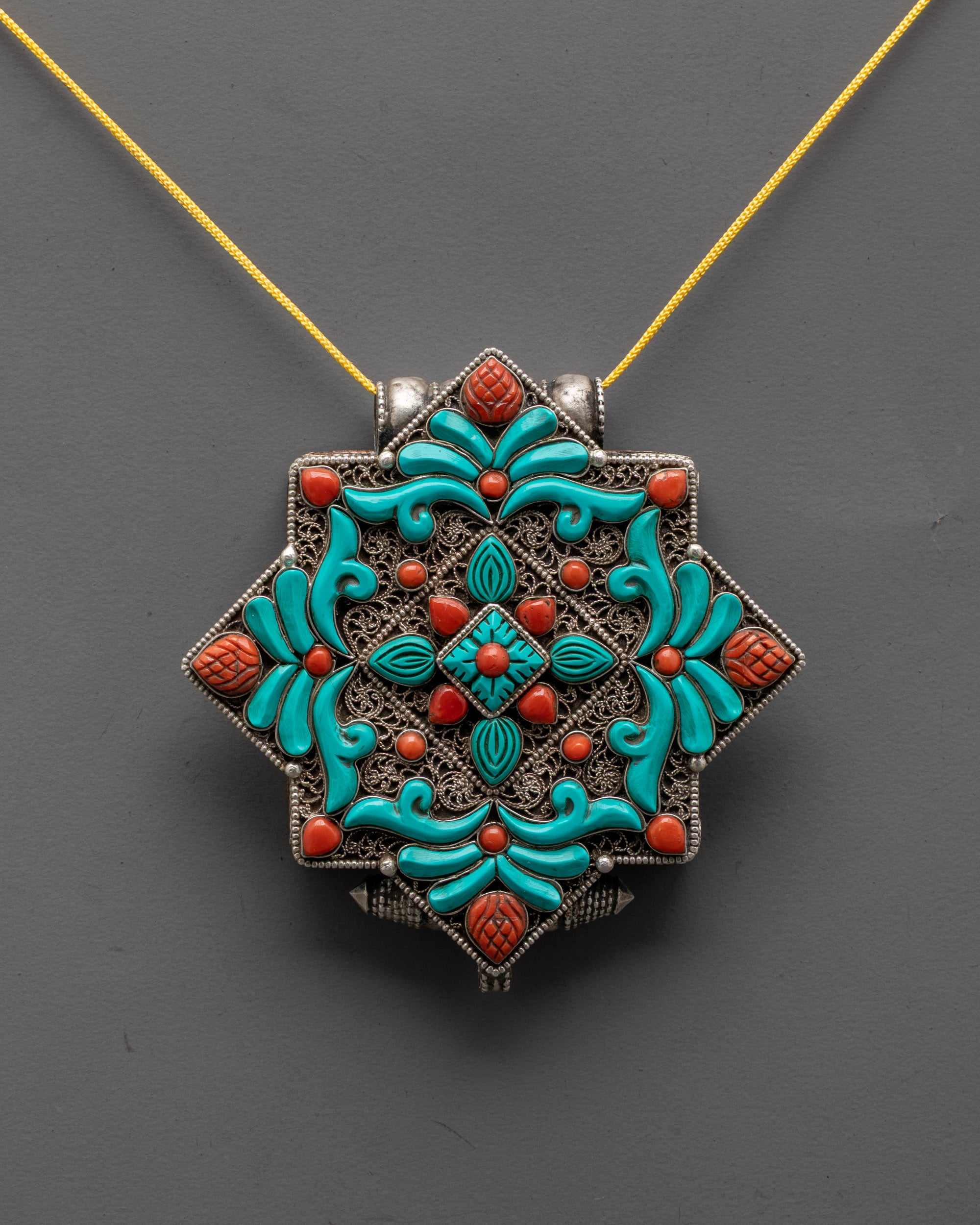 front view of authentic tibetan locket in silver with coral turquoise stones and filigree design