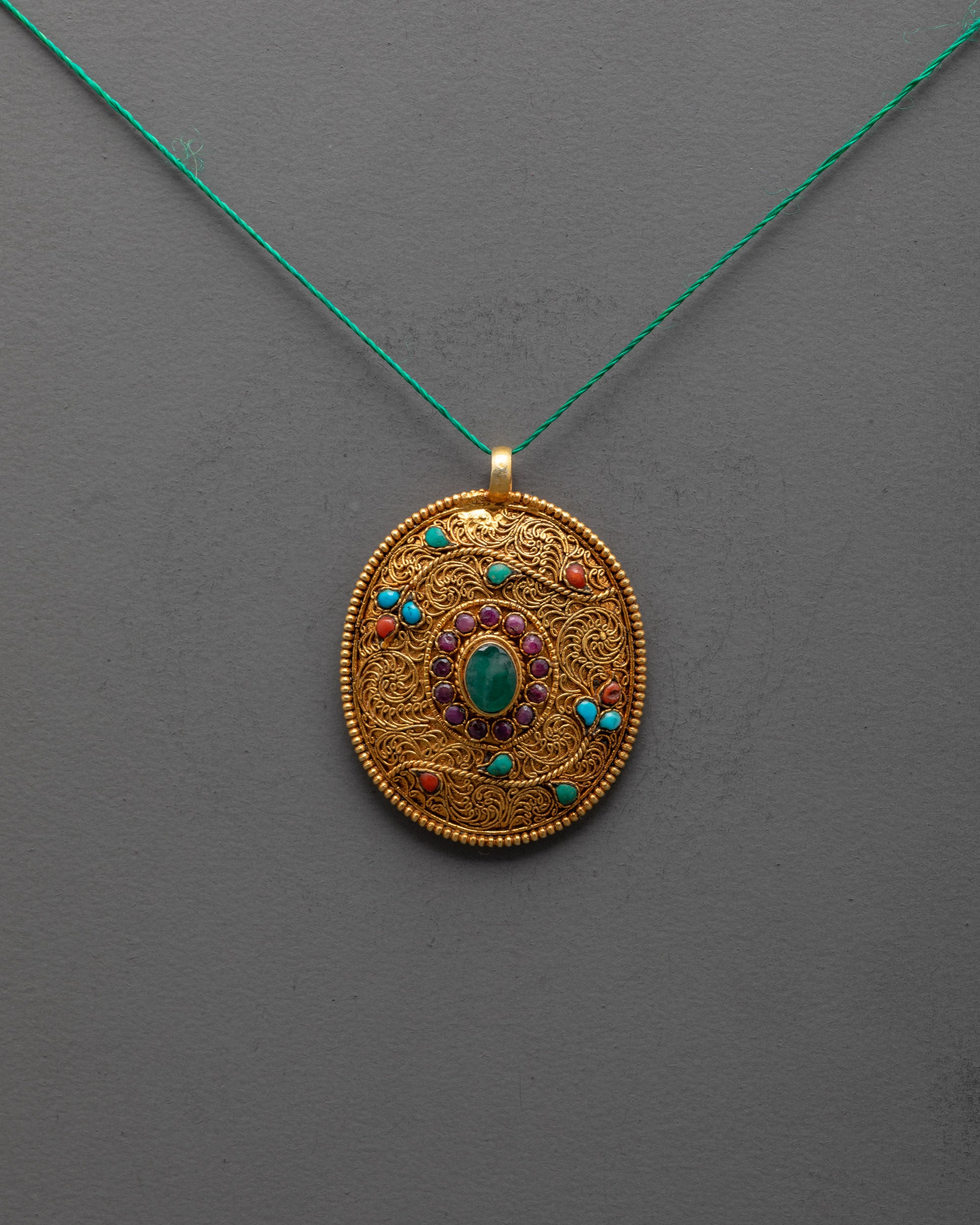 front view of gold-plated flower locket with emerald and semi-precious stones detailed filigree