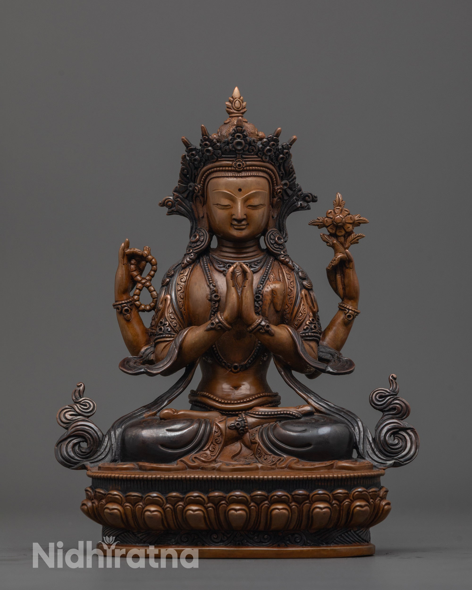 front view of oxidized Lokeshvara statue seated on lotus throne with four arms and sacred items