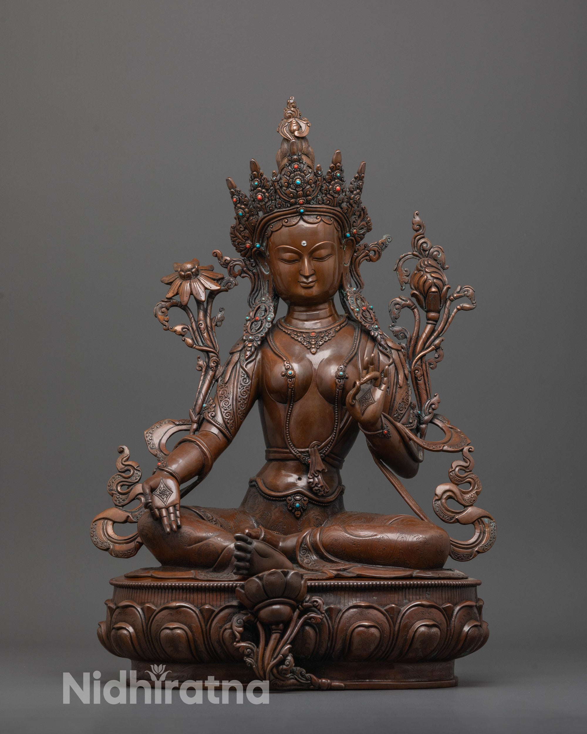 front view of oxidized green tara statue seated in royal ease on lotus base
