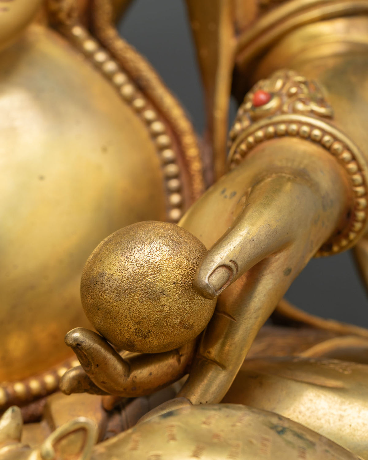 Ganesh hand holding a sweet modak symbolizing spiritual fulfillment, fire-gilded copper detail