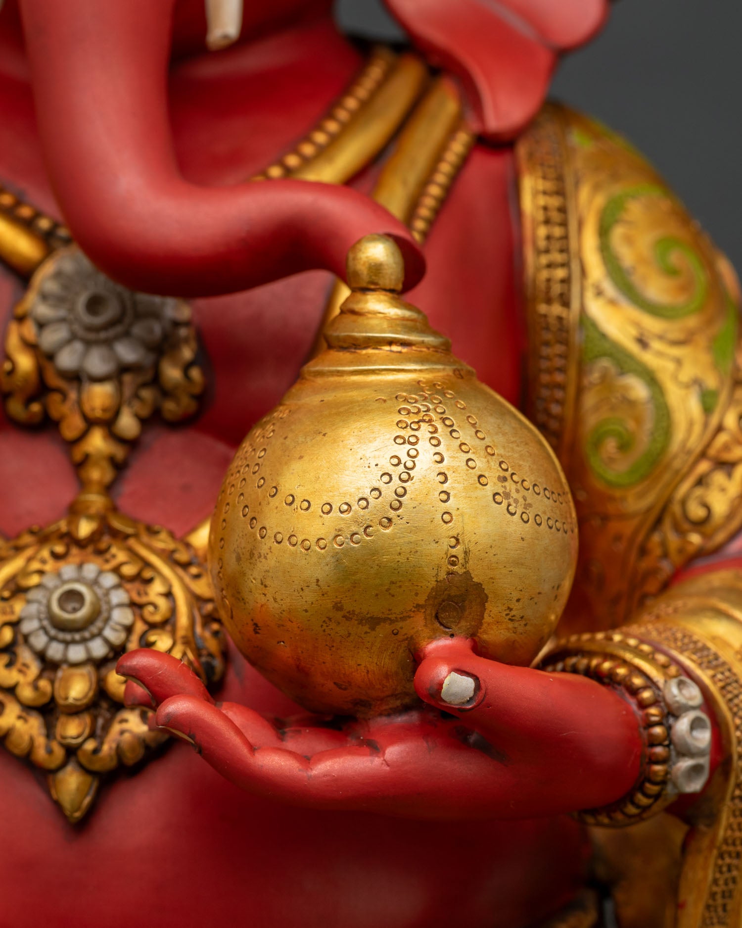 Ganesha statue hands cradling golden Kalasha pot, intricate gold detailing