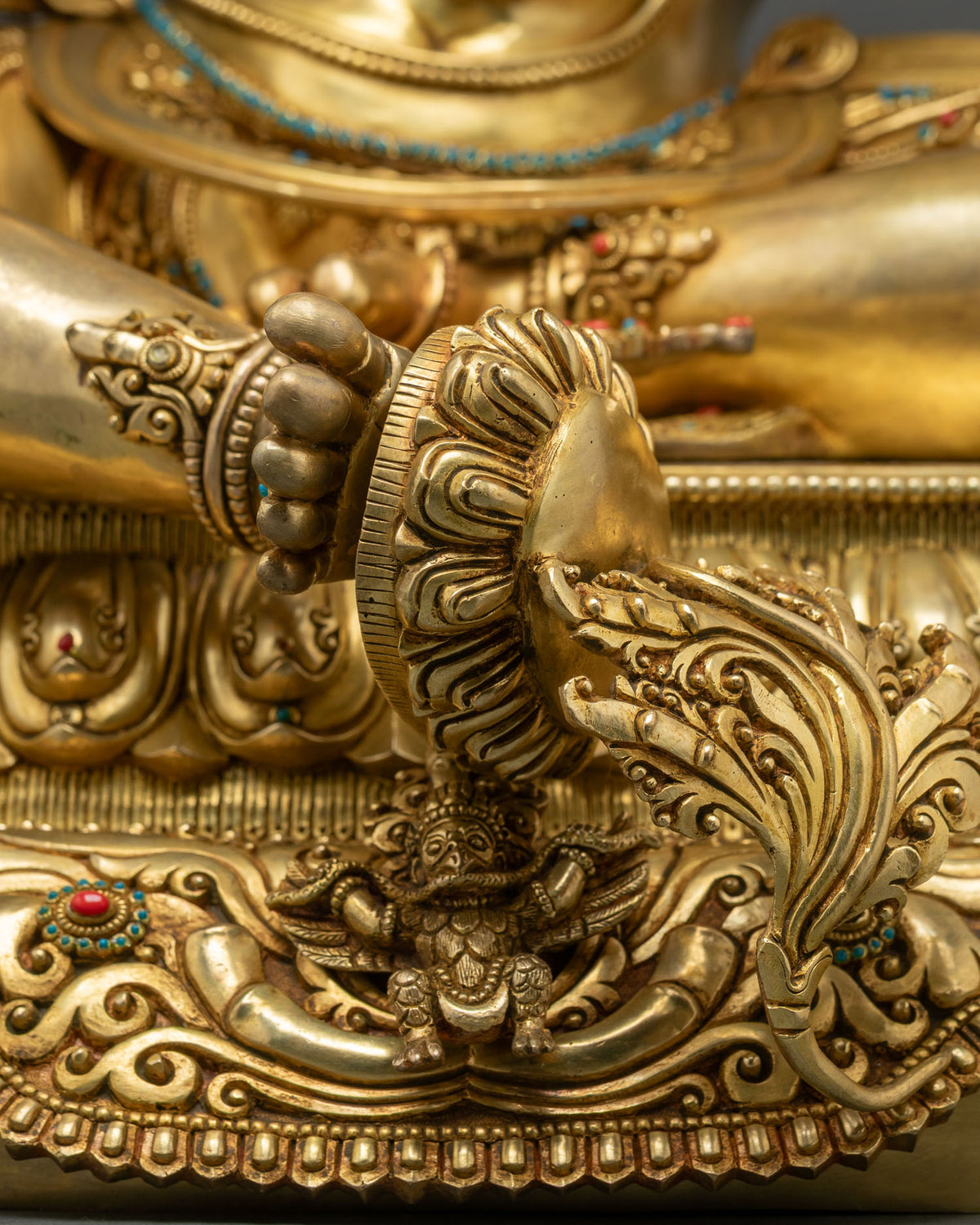 Garuda icon close-up carved on the lotus pedestal of Green Tara statue, handcrafted gold detail