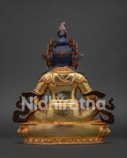 Gold gilded Dzambhala Buddhist statue seated on lotus pedestal for altar and meditation