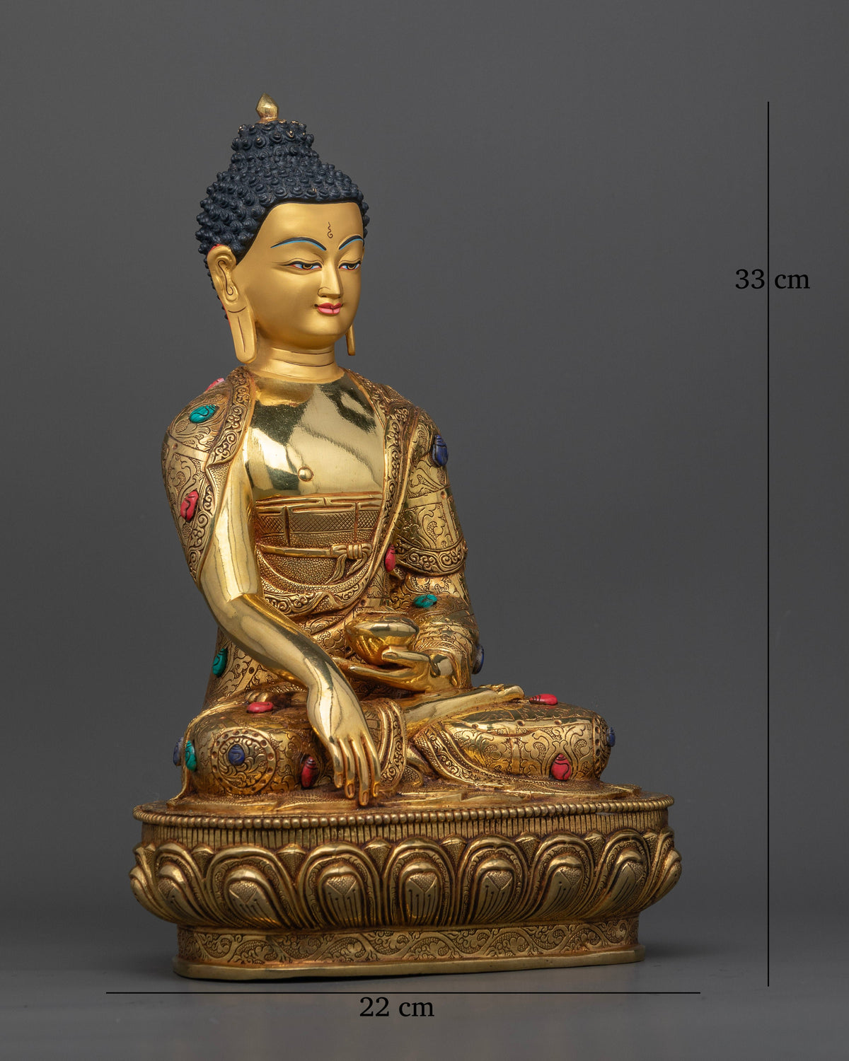Gold gilded Shakyamuni Buddha sculpture featuring an intricately carved monastic robe with floral motifs and semi precious stones.