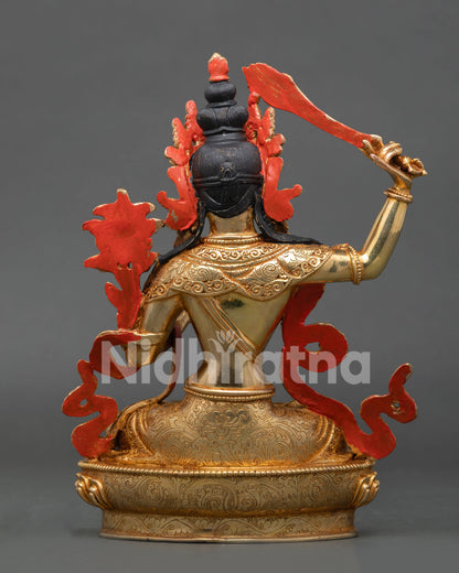 Gold-painted face of Manjushri Statue with serene expression and finely detailed Himalayan artistry