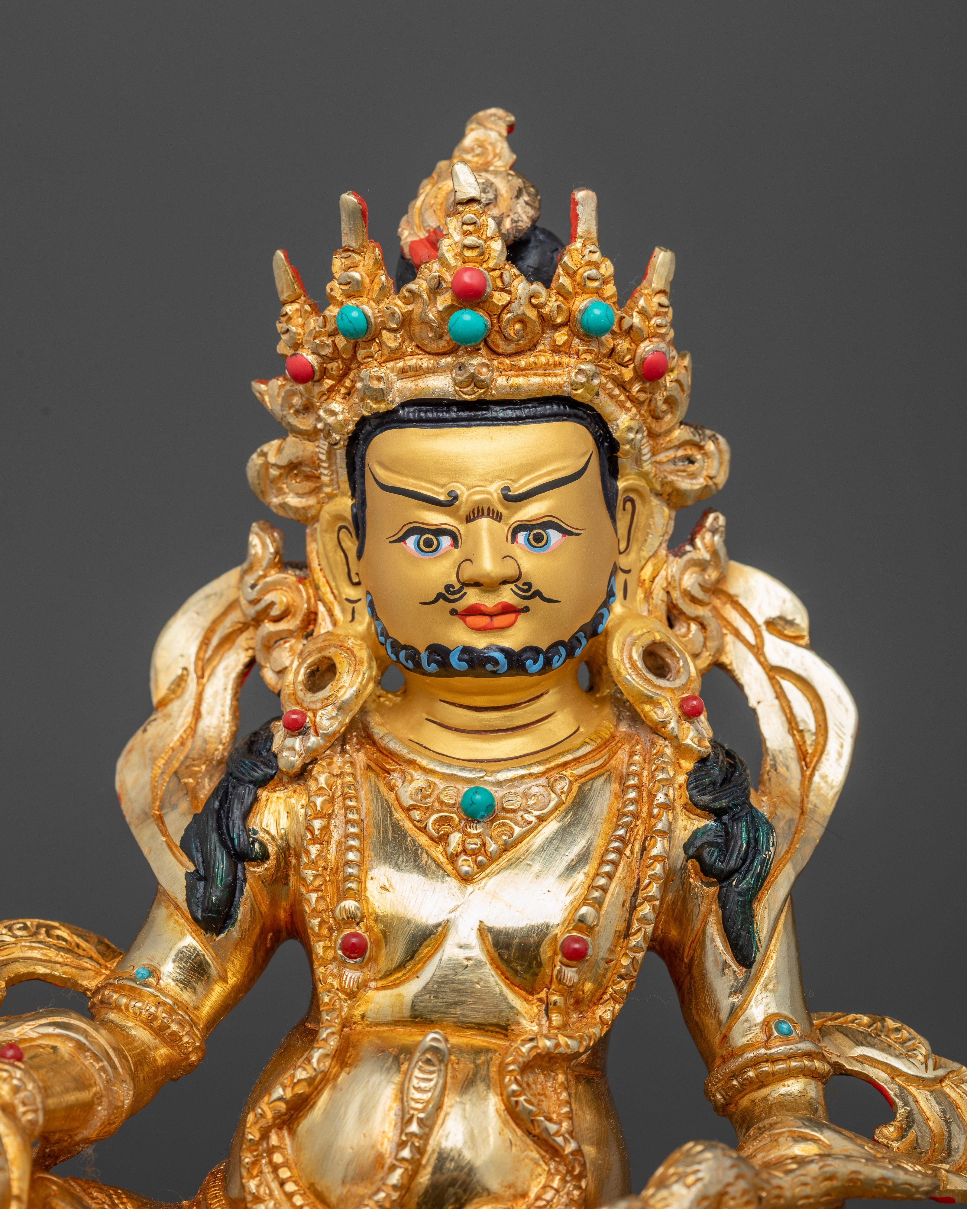 Gold-painted face of Nepalese Dzambhala Statue adorned with hand-set semi-precious stones
