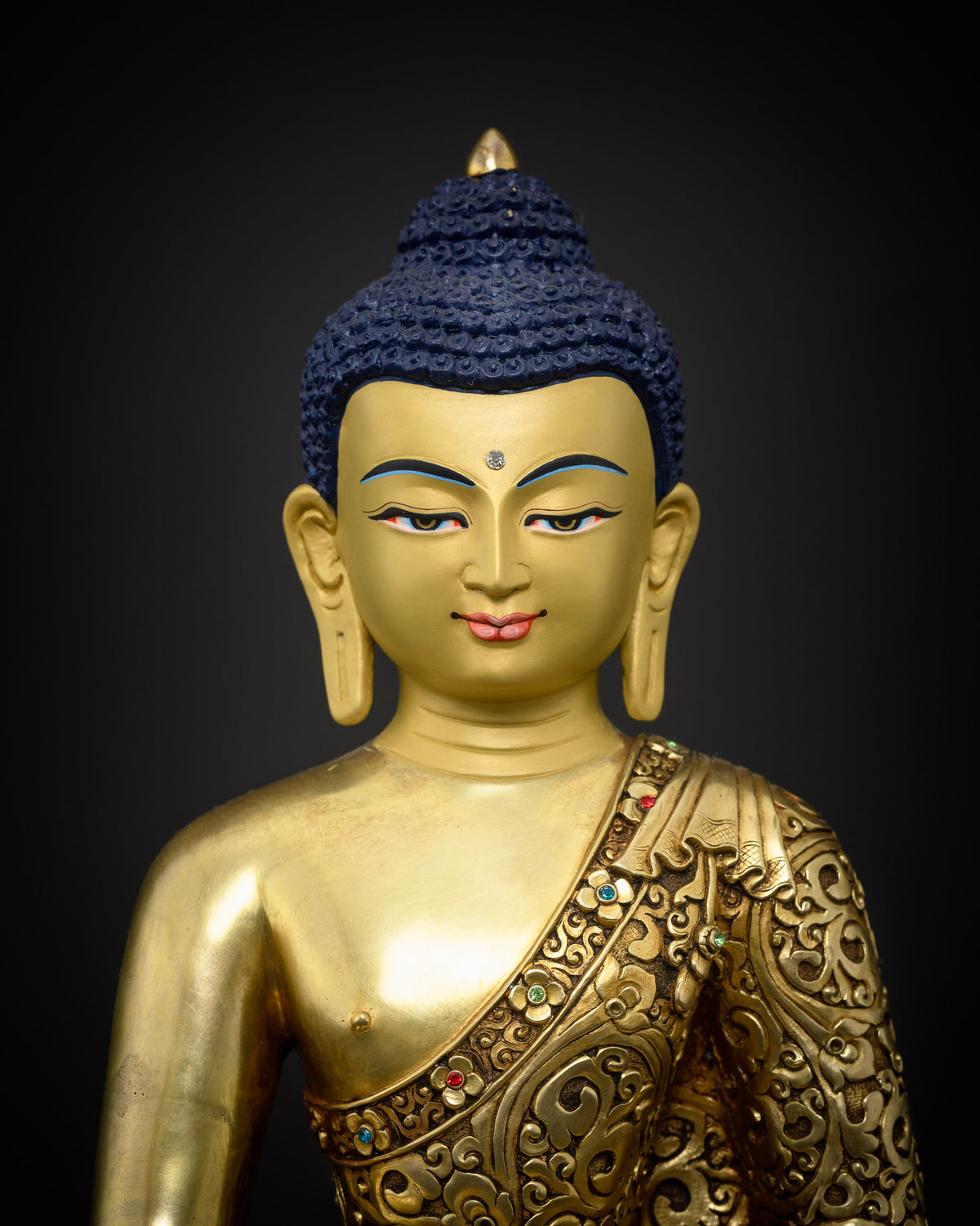 Golden Shakyamuni Buddha sculpture featuring a finely gold painted face and intricate floral carvings on the monastic robe.